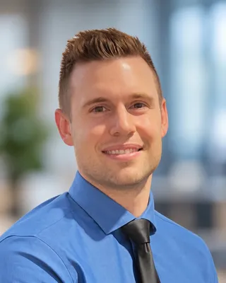 Matt, the founder of CueBuilt, smiling, in a blue shirt and dark tie.